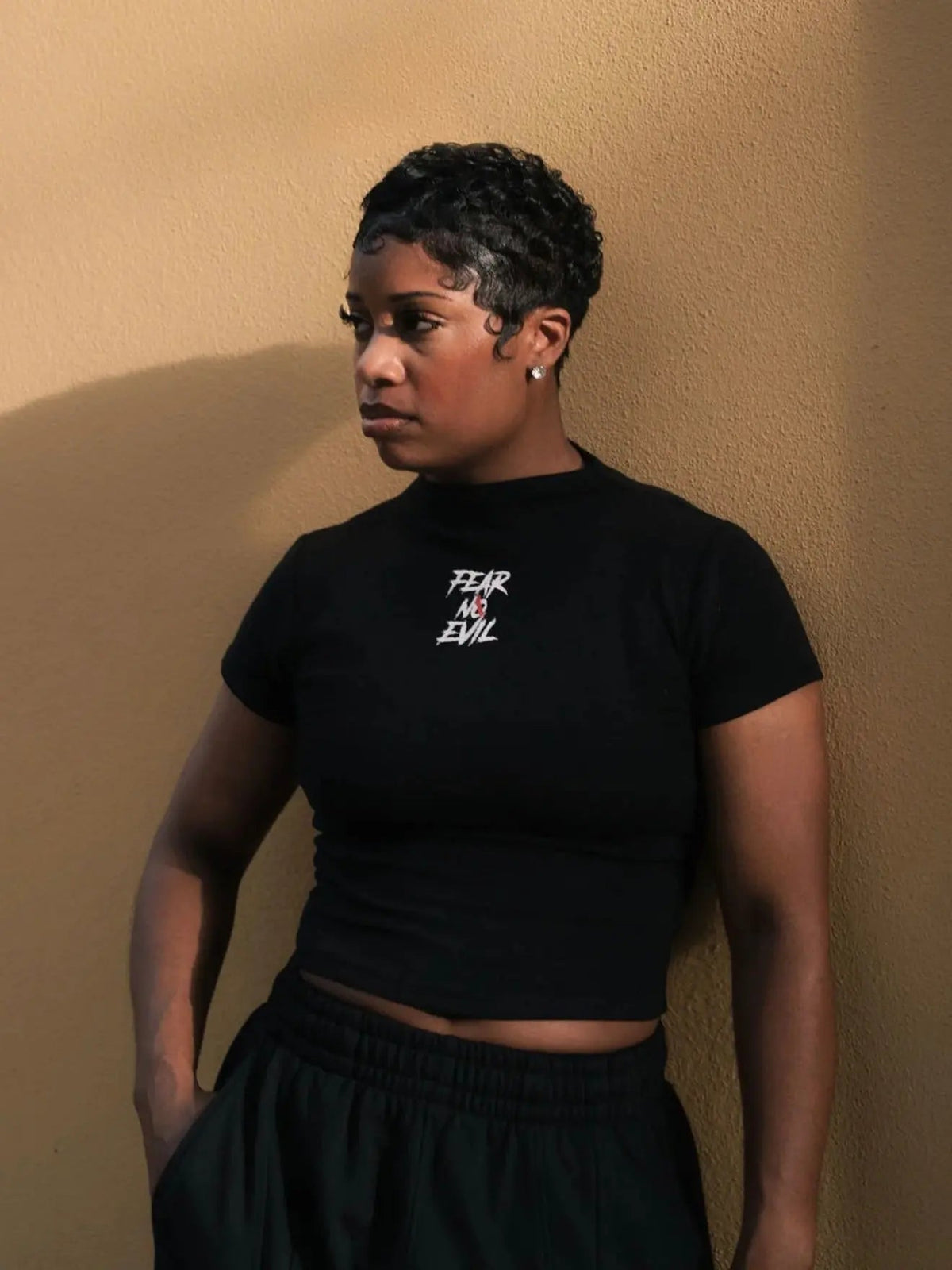 Performance tees vs cotton tees showcased by a model in a black crop top with "FEAR NO EVIL" print.