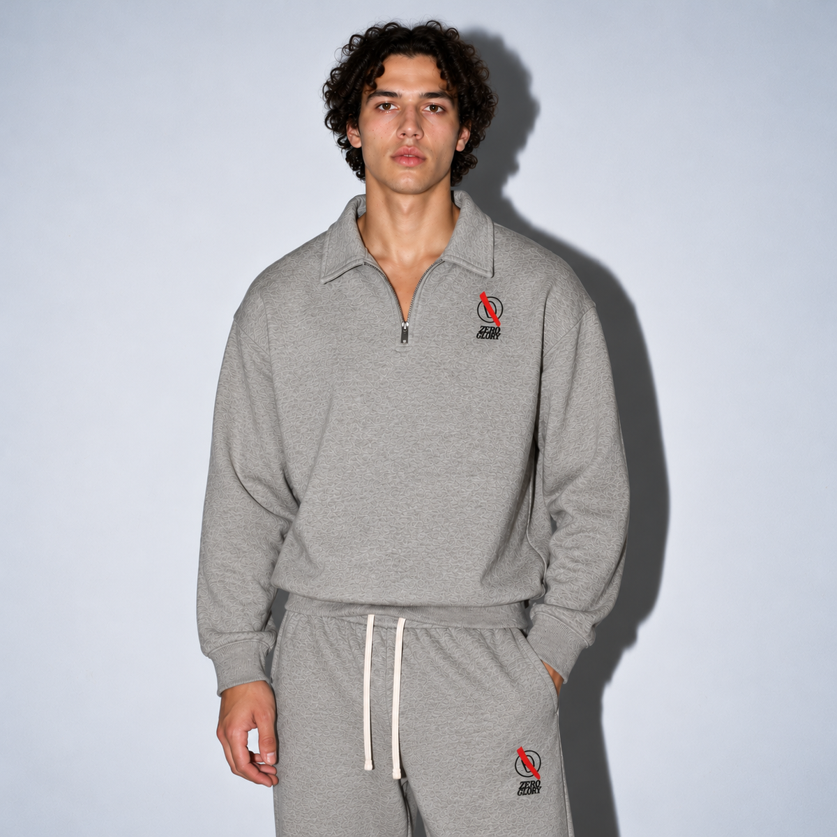 Male model wearing a grey Zero Glory quarter-zip sweatshirt and matching joggers with embroidered branding