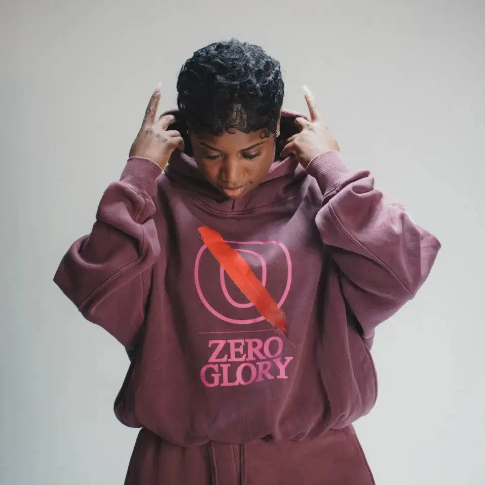 Person wearing a maroon hoodie with 'Zero Glory' text and logo on a plain background