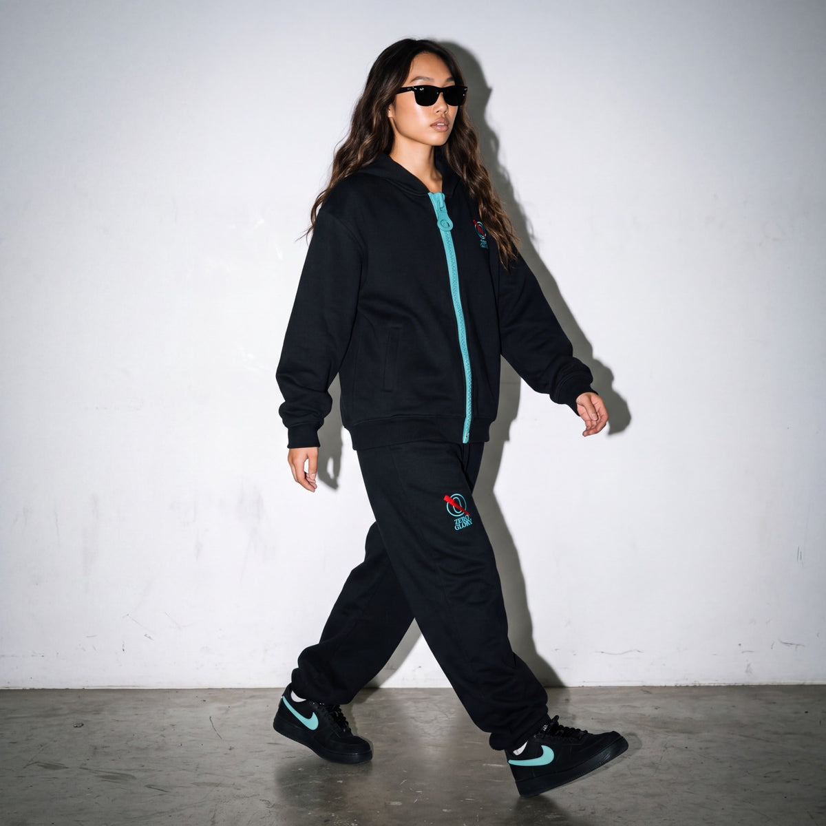 Woman wearing the Zero Glory Unisex Barrel Leg Sweatpants in Black with the Chunky-Zip Hoodie