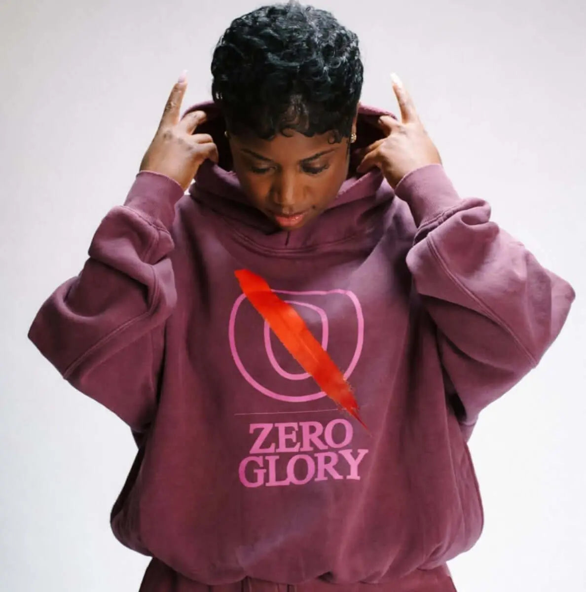 woman wearing a purple hoodie with 'ZERO GLORY' text, reflecting on the meaning of giving God glory in life.