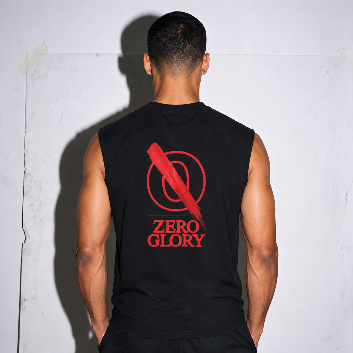 Back view of a man wearing a vintage boxy raw hem tank top by Zero Glory in black with bold logo.