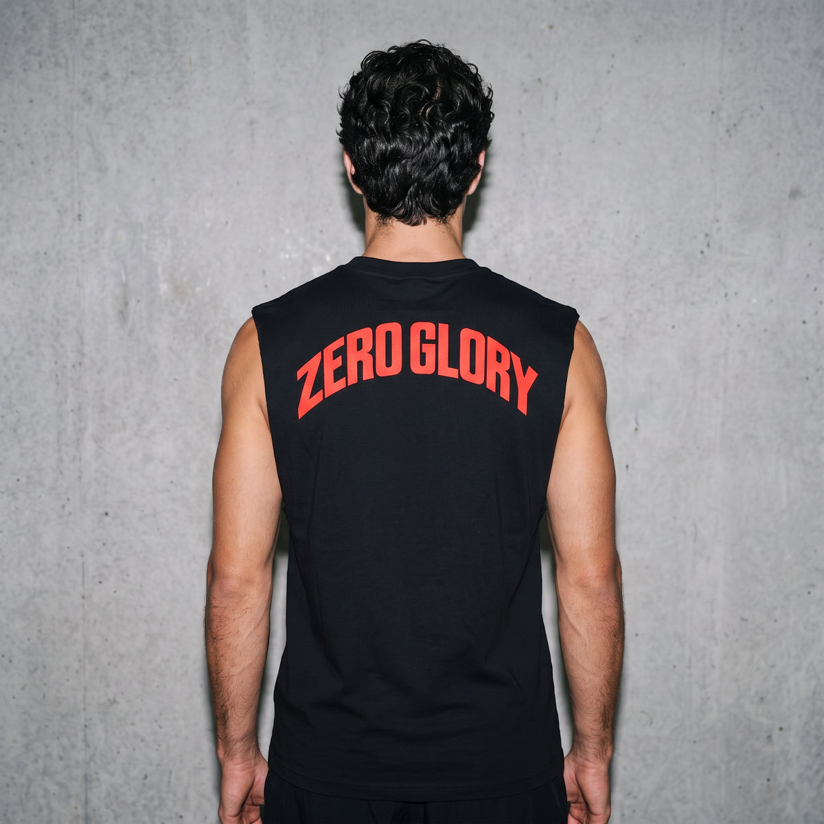 Back view of a man wearing a Vintage Gym Graphic Tank Top with 'ZERO GLORY' text.