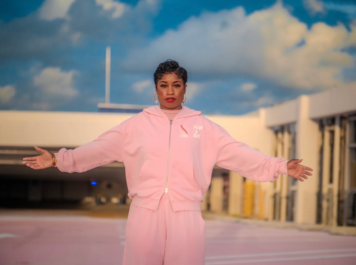 Woman wearing a pink Zero Glory tracksuit, showcasing faith-inspired streetwear.