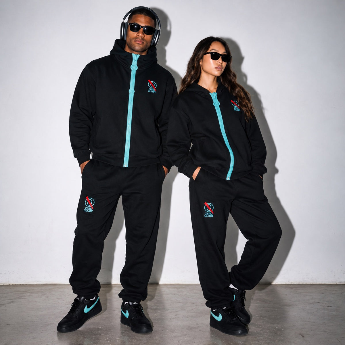 Man and woman wearing the Zero Glory Chunky-Zip Hoodie and Barrel Leg Sweatpants set in Black